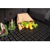 на картинке открытый багажник, на коврике перевернутый бумажный пакет с продуктами и стоящими цветами в вазонах