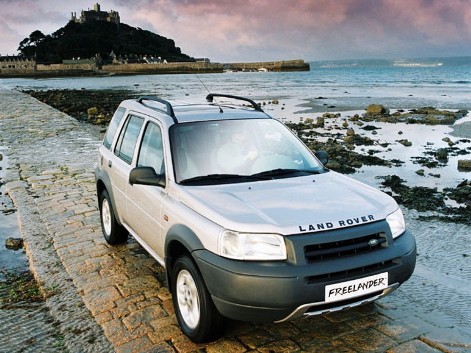 На фото автомобиль Land Rover Freelander первого поколения серого цвета проезжает возле побережья