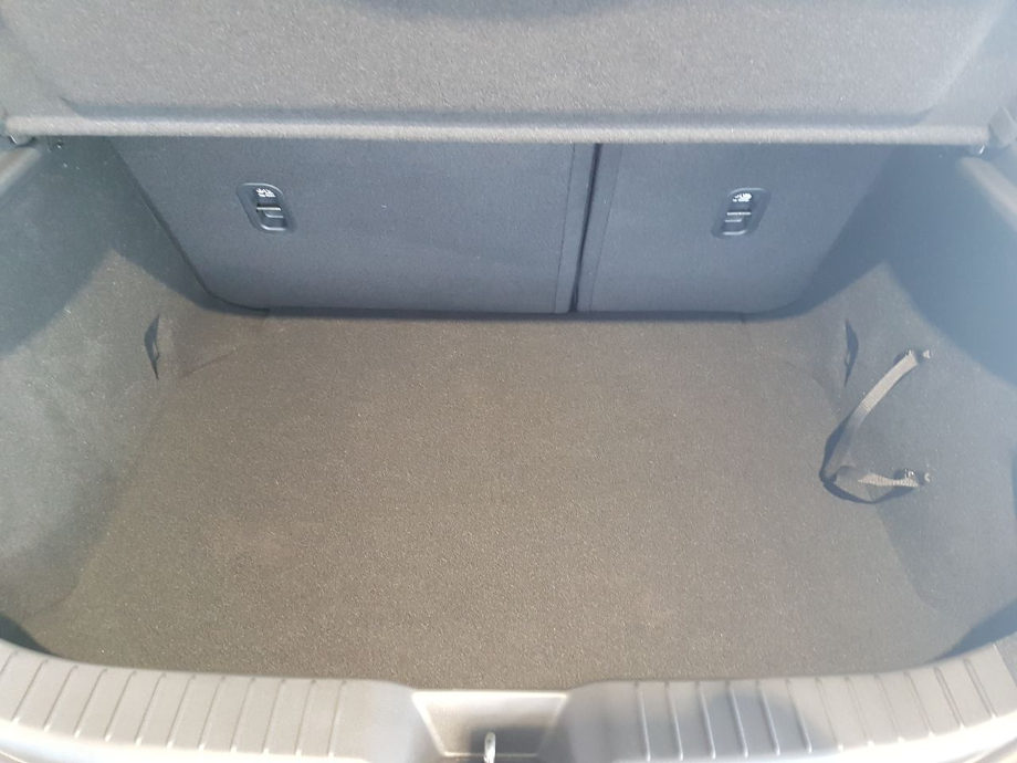На фото об'ємний багажник автомобіля Мазда 3 сірого кольору без килимка із заводською оббивкою багажника