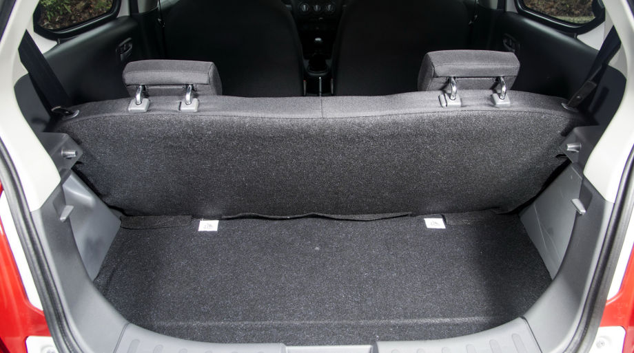 На фото відкрите багажне відділення автомобіля Suzuki Alto білого кольору.