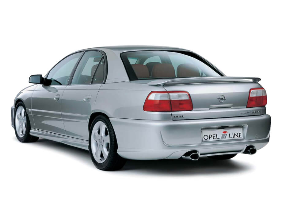На фото автомобиль Опель Омега Б, серебристого цвета на белом фоне.