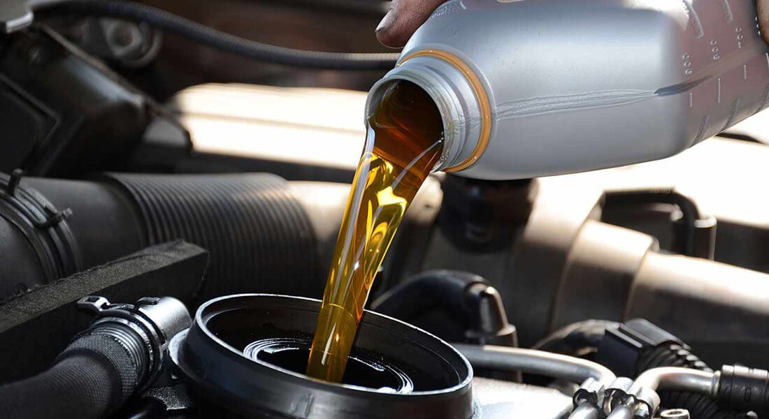 На фото видно как производится замена масла в автомобиле. Мастер наливает масло в специальную емкость