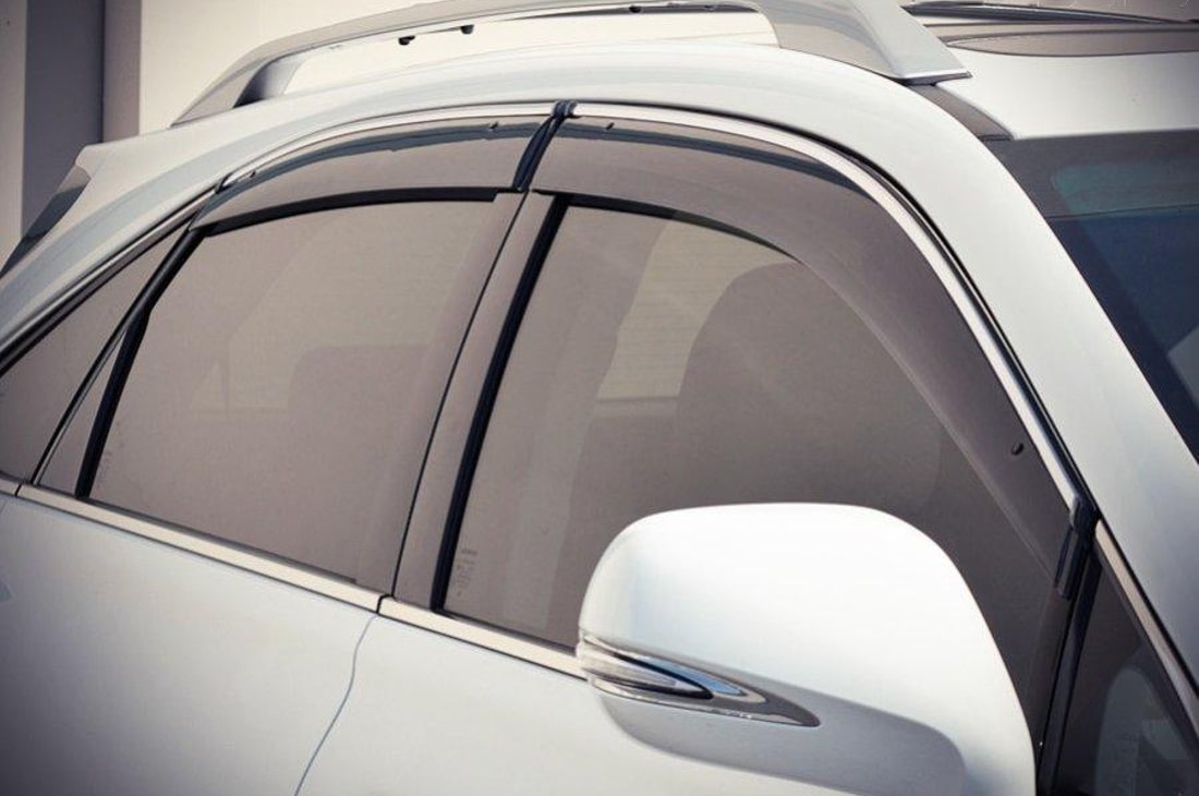 На фото закриті пасажирські вікна, на яких встановлені вітровики, автомобіля сріблястого кольору