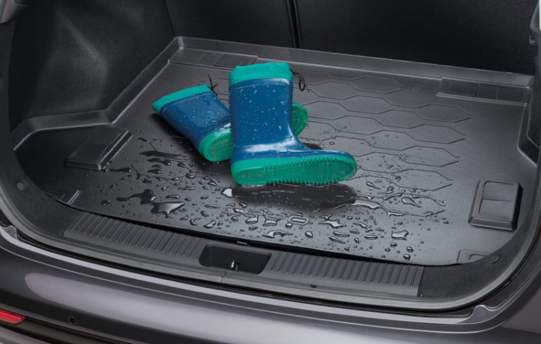 На фото на мокром полиуретановом коврике в багажнике автомобиля лежат резиновые сапоги бирюзового цвета