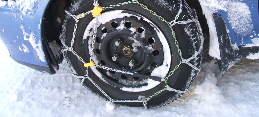 На фото крупним планом ланцюги на колесі в засніжену зиму